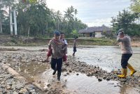 Personel Batalyon C Pelopor Brimob Polda Gorontalo yang dipimpin oleh IPDA Arifin Mahadjani turun langsung membantu masyarakat serta anak-anak sekolah menyeberangi sungai. Foto: Istimewa